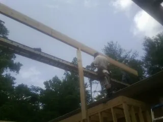 Carpenter setting a ridge beam over a new addition frame — Ice Dam Removal by Roofing Brothers in Taberg