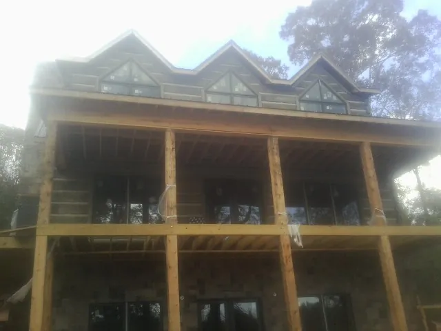 Dormers and porch framing on a large log home under construction — Roof Coating work by our crew in Taberg