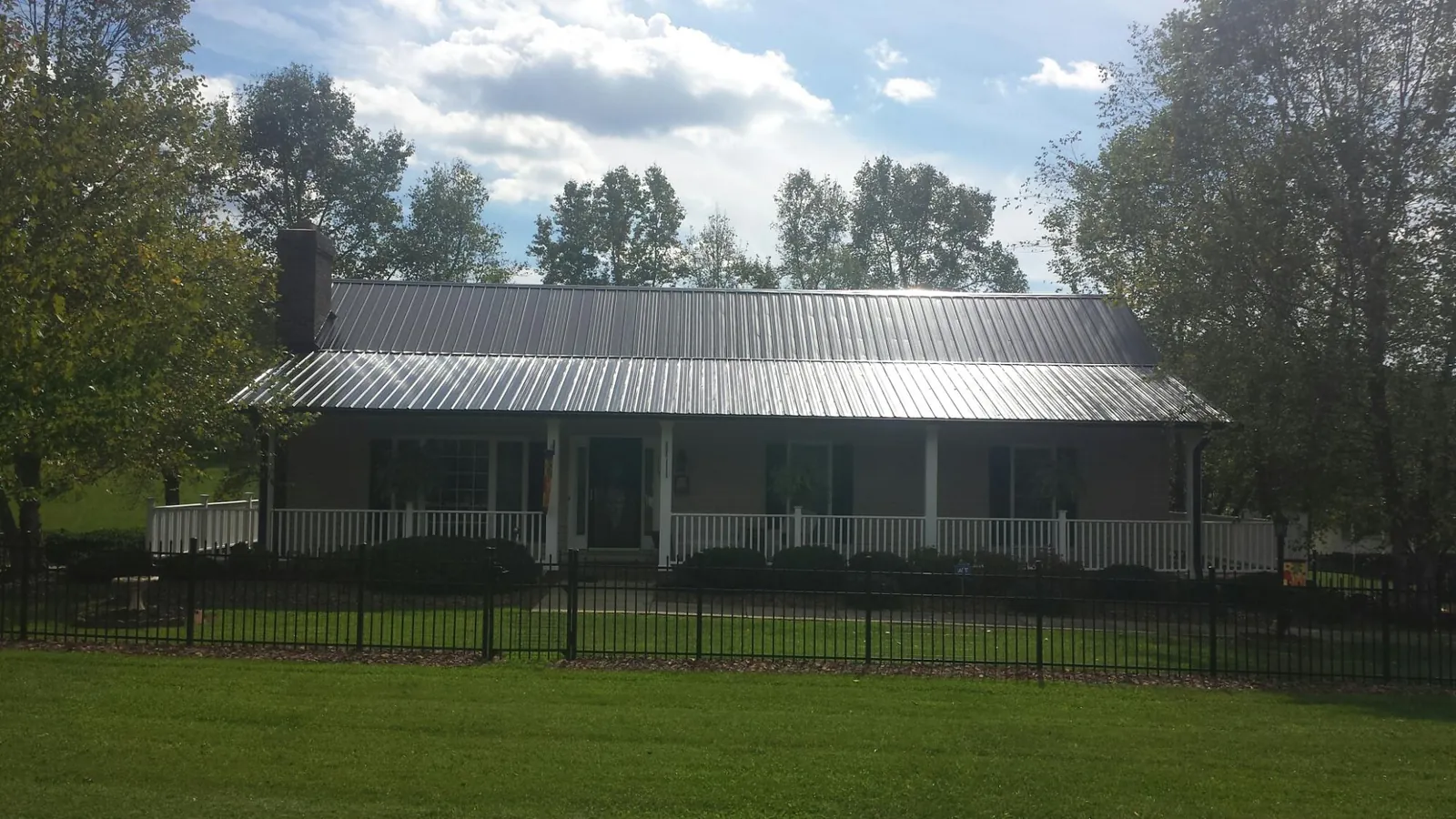 Gray metal roof on a brick ranch with a full width front porch — Gutter Guard Installation work by our crew in Taberg