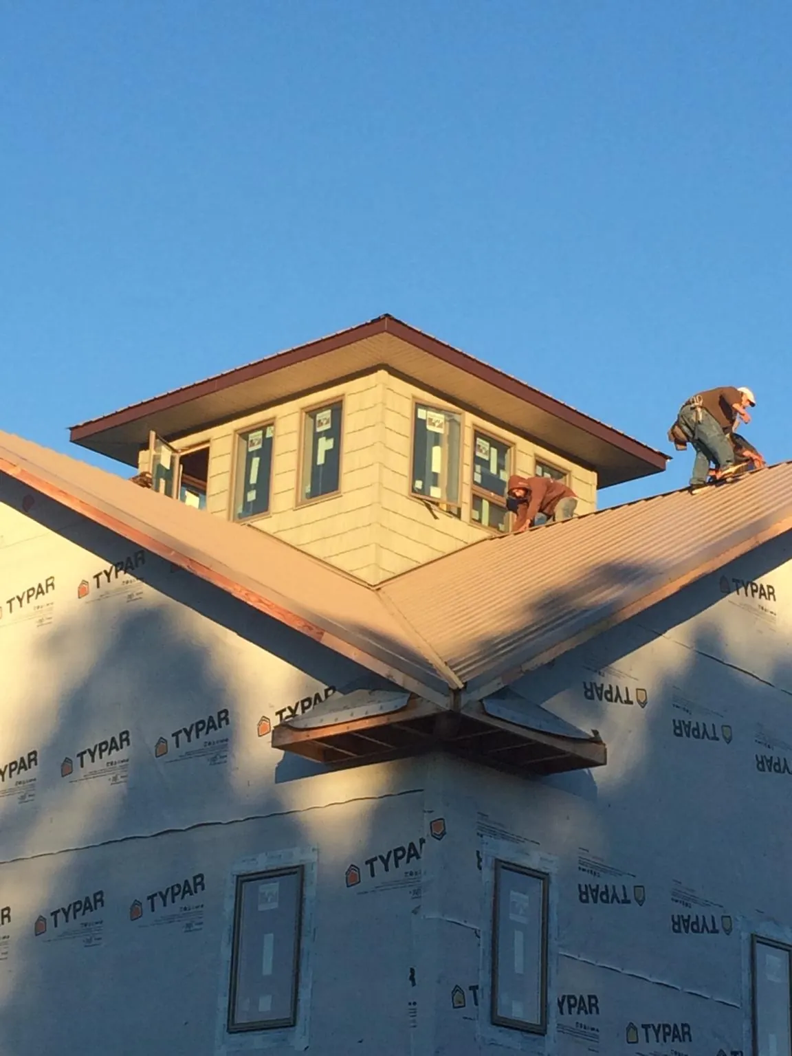 Roofers working around a rooftop cupola on a new metal roof at sunset — Roof Waterproofing in Taberg by Roofing Brothers